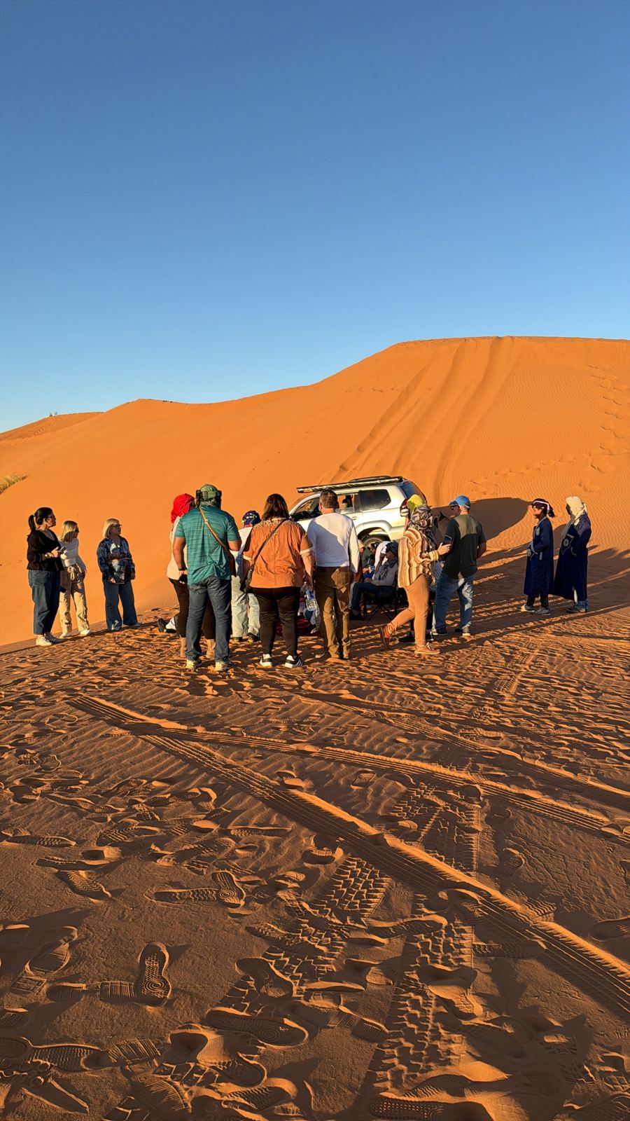 Viajeros con un 4x4 junto a una gran duna en Merzouga